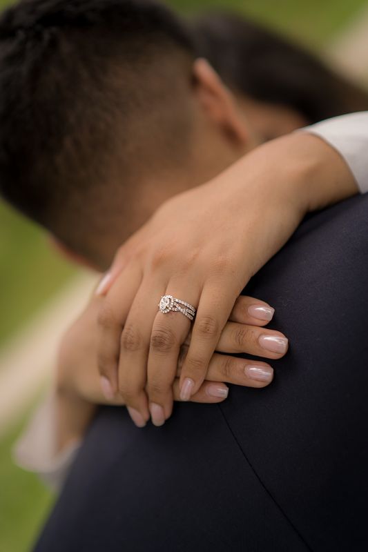 Close-up of an engagement ring on a hand resting on a partner's shoulder