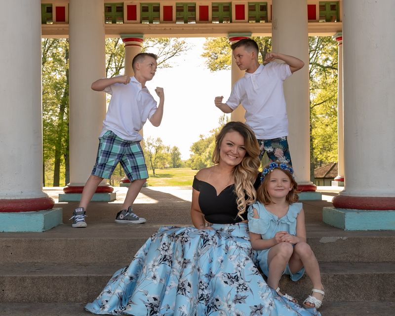 Mother and her three kids posing playfully between white columns
