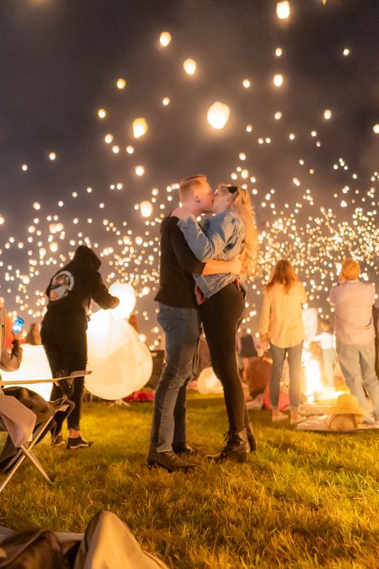 Couple embracing beneath thousands of glowing lanterns at night