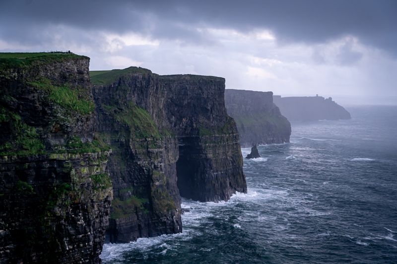 Tall dark sea cliffs above a rough, misty sea